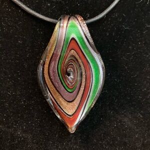 Glass pendant on cord with sterling silver clasp and adjustable chain.